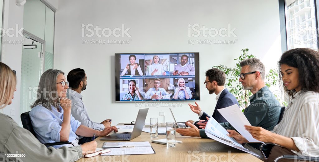 Diversi dipendenti dell'azienda che effettuano videochiamate per conferenze di lavoro online sul monitor dello schermo televisivo nella sala riunioni del consiglio. Presentazione in videoconferenza, concetto di formazione aziendale di gruppo virtuale globale.